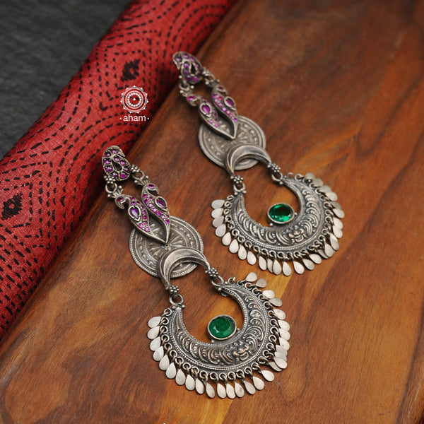 Shivneri chandbali earrings with elegant peacock motifs. Handcrafted in 92.5 sterling silver with emerald and rani pink coloured stone setting. These are long yet very light statement earrings. 