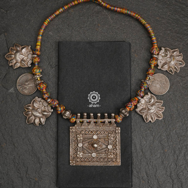 Tribal silver neckpiece handcrafted by threading together multiple tribal . This necklace truly exemplifies the continuity of the traditional prototypes. A beautiful vintage neckpiece with some distinct pieces threaded together.  The center rectangle amulet represents a family unit. There are 4 distinct rare floral motif on each sides of the center piece and two vintage coins from pre independent India. 