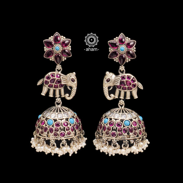 Handcrafted statement Nrityam jhumkie earrings in 92.5 sterling silver. With elegant elephant and floral motifs. Enhanced with kemp and turquoise coloured stone setting, hanging cultured pearls. 