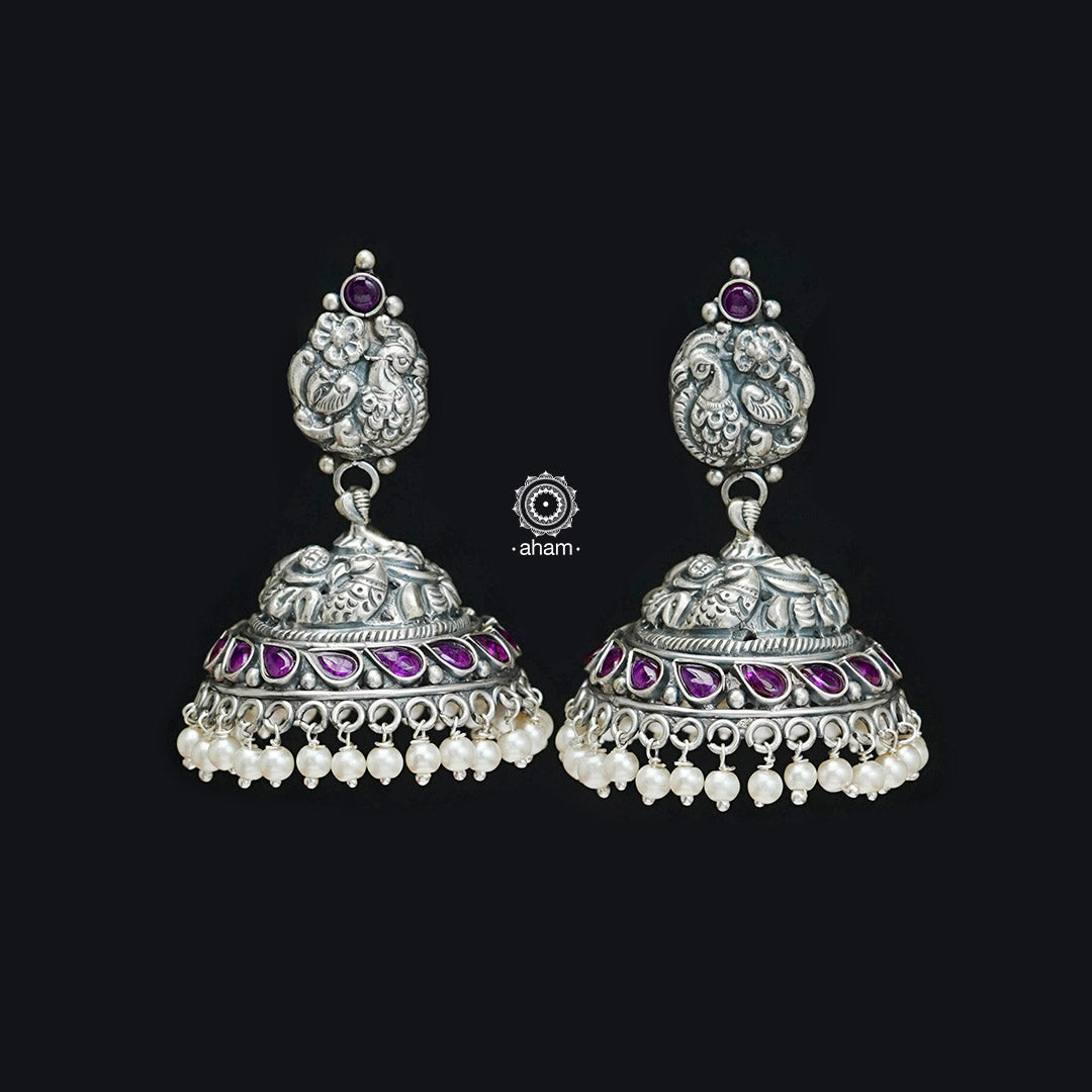 Elegant Nakshi peacock jhumkie earrings with intricate work. Handcrafted by skillful artisans in 92.5 sterling silver, with maroon kemp stone and cultured pearls.