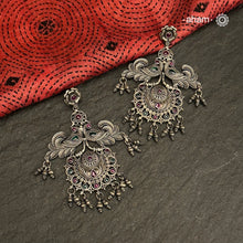 Mewad double peacock earrings handcrafted in 92.5 sterling silver with green and maroon stones. An ode to the glorious state of Rajasthan. Perfect pair of elegant danglers for your ethnic outfits. 