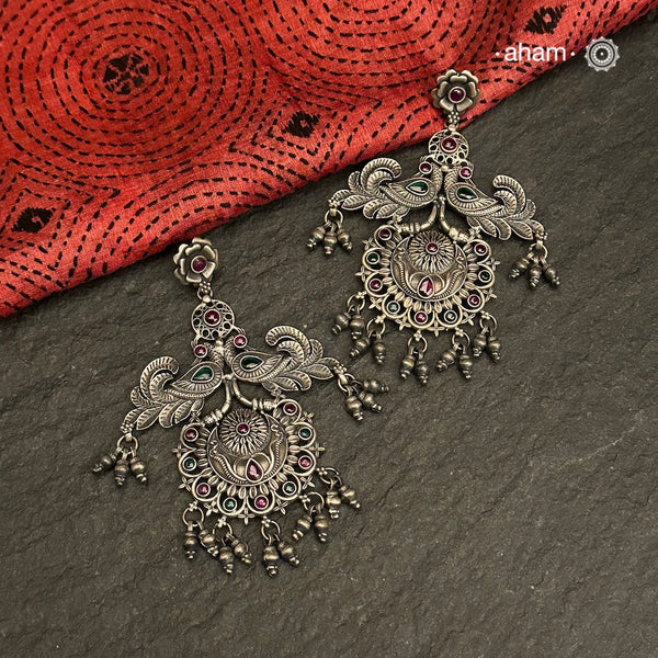 Mewad double peacock earrings handcrafted in 92.5 sterling silver with green and maroon stones. An ode to the glorious state of Rajasthan. Perfect pair of elegant danglers for your ethnic outfits. 