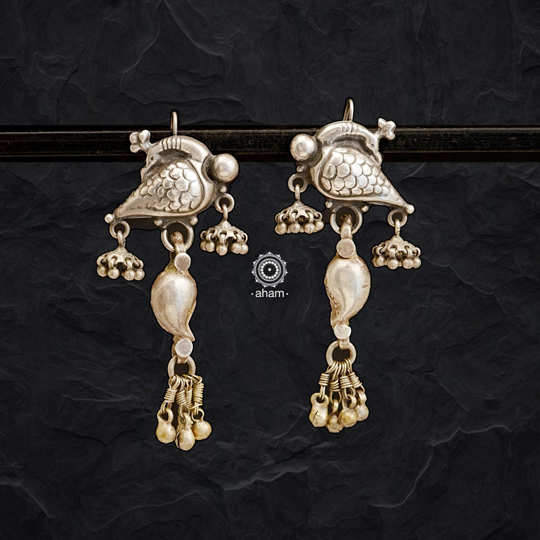 These Mewad Peacock Silver Earrings are a stunning union of classic vintage silver and new 92.5 silver elements. A graceful peacock top is combined with intricate paisley patterns, traditional ghungroos, and two delicate jhumkies. An extraordinary accessory for any occasion. 
