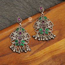 Mewad double peacock earrings with green and pink stone highlights. Handcrafted in 92.5 sterling silver with intricate work and dangling ghungroos. An ode to the glorious state of Rajasthan. 