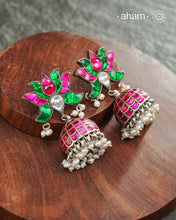Handcrafted in 92.5 sterling silver with dangling cultured pearls, rani (pink) and kundan work.These festive lotus jhumkie earrings will add more bling and drama to your jewellery collection.