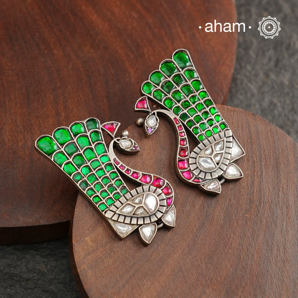 These festive peacock silver earrings are expertly crafted in 92.5 silver, with exquisite green and pink kundan detailing. Elevate any look with these stunning earrings that are sure to make a statement.