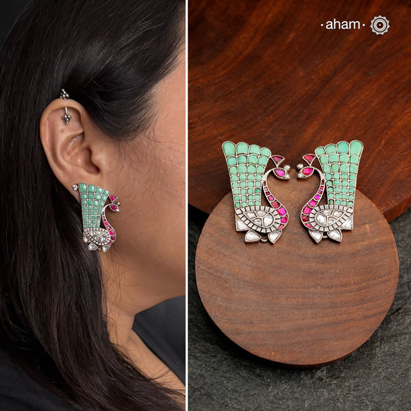 These festive peacock silver earrings are expertly crafted in 92.5 silver, with exquisite green and pink kundan detailing. Elevate any look with these stunning earrings that are sure to make a statement.