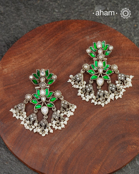 Handcrafted in 92.5 sterling silver with floral motifs and green kundan setting. These festive lotus earrings are show stoppers and will add drama to your outfit.