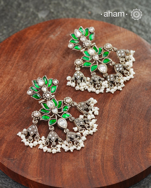 Handcrafted in 92.5 sterling silver with floral motifs and green kundan setting. These festive lotus earrings are show stoppers and will add drama to your outfit.