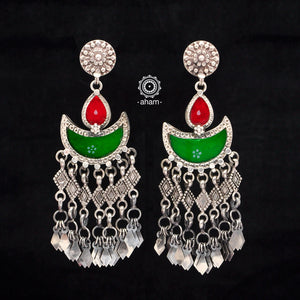 Statement Rang Mahal green & red diya earrings with dangling charms, handcrafted in 92.5 sterling silver. The magic that happens when glass, silver and a pop of colour come together.