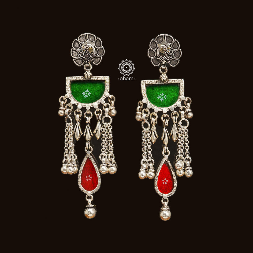 Expertly crafted from 92.5 sterling silver, these Rang Mahal earrings feature a vibrant blend of green and red hues. With a peacock stud design, they effortlessly combine glass and silver to create a stunning pop of color. Make a bold statement with these beautiful, handcrafted earrings that are sure to become a favorite in your collection.