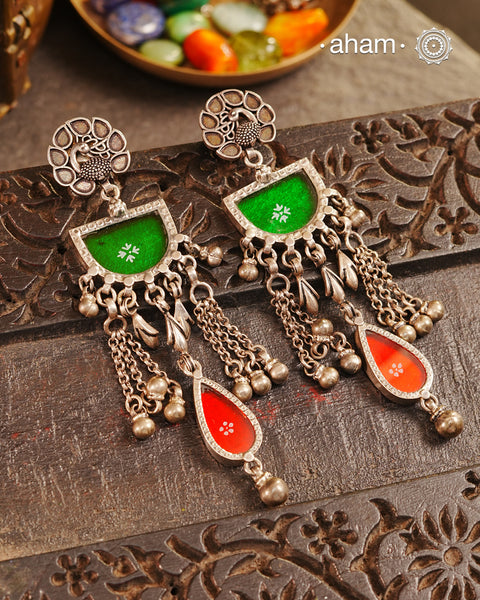 Expertly crafted from 92.5 sterling silver, these Rang Mahal earrings feature a vibrant blend of green and red hues. With a peacock stud design, they effortlessly combine glass and silver to create a stunning pop of color. Make a bold statement with these beautiful, handcrafted earrings that are sure to become a favorite in your collection.