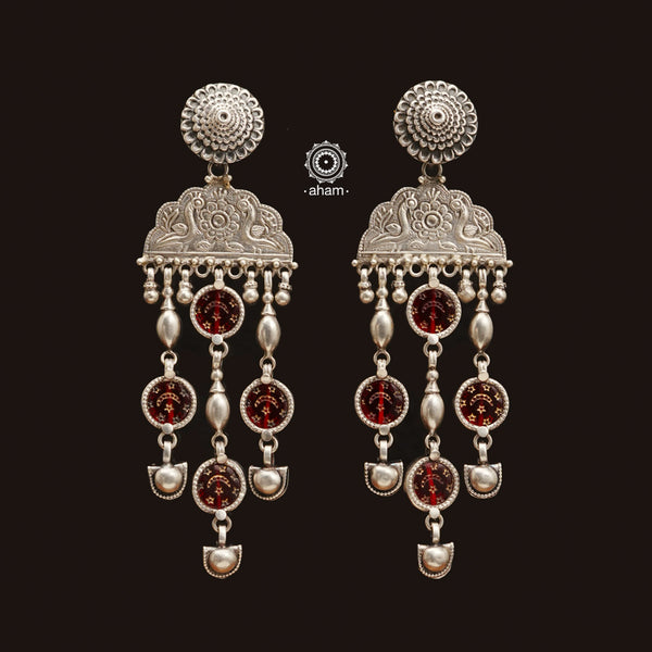 Handcrafted with 92.5 sterling silver, these Peacock Rang Mahal earrings feature a stunning red drop design that brings together glass, silver, and a pop of colour. With their lightweight design, these show stopper earrings are not only mesmerizing but also comfortable to wear. Elevate your style with these unique and beautifully crafted earrings.