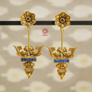 These Double Peacock Gold Polish Silver Earrings offer a stunning blend of European and Indian design. Delicately crafted peacocks adorn each side, highlighted with vibrant blue kundan. Elevate any outfit with this fusion of artistry and elegance.