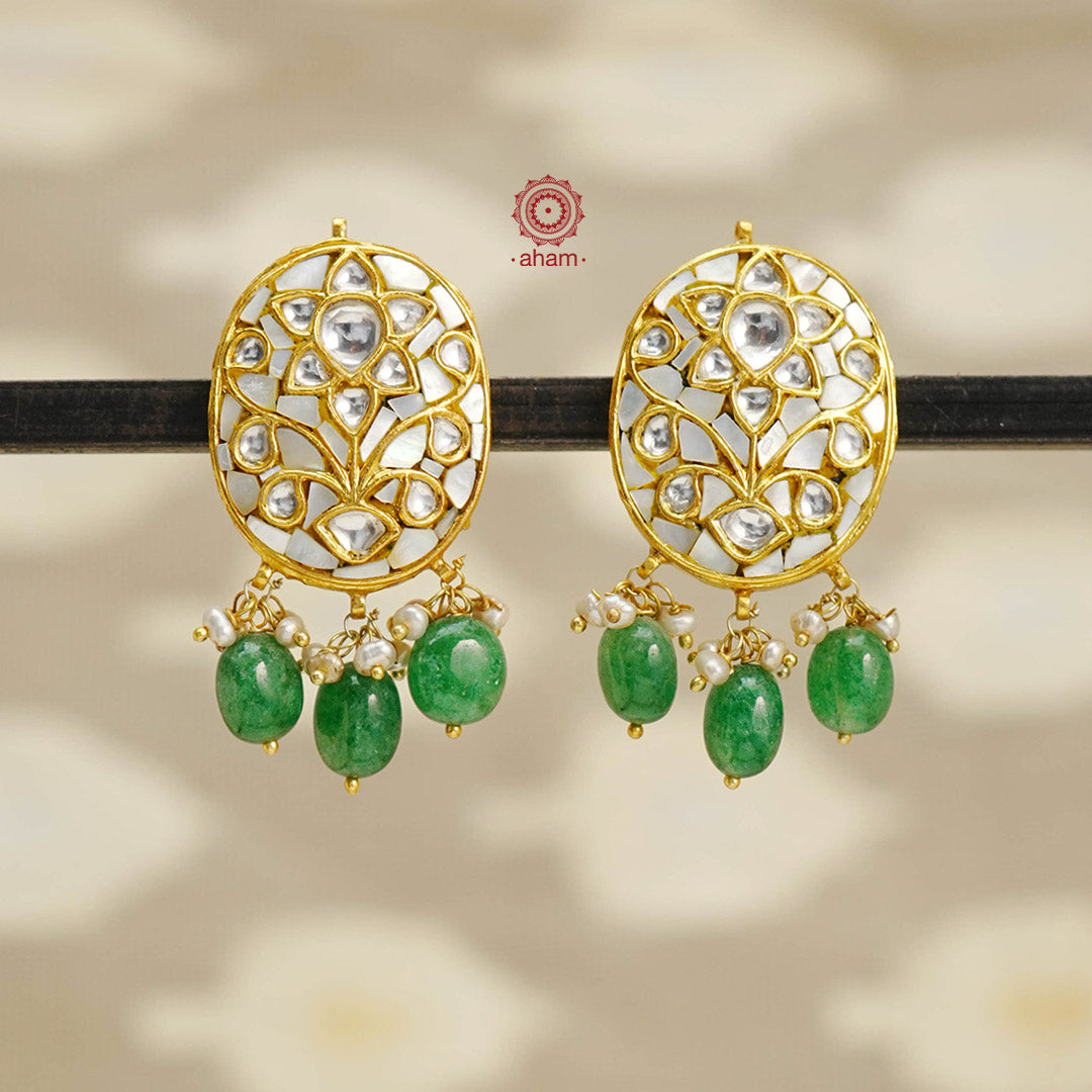 Crafted with 92.5 silver and dipped in gold, these earrings feature elegant mother of pearl and kundan studs, accented with delicate pearls and green stones. Perfect for adding sophistication and a touch of luxury to any outfit.