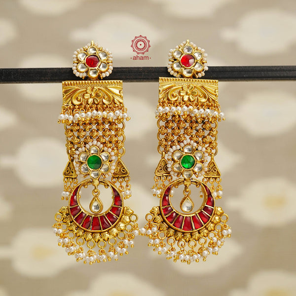 Experience the best of both worlds with our Kundan Gold Polish Silver Earrings. These statement earrings combine the boldness of a chandelier earring with the elegance of a chandbali. With its unique design, these earrings are sure to stand out and make a statement. Elevate any outfit with this one-of-a-kind piece. Crafted in silver with the perfect kundan work, pearls and gold polish. 