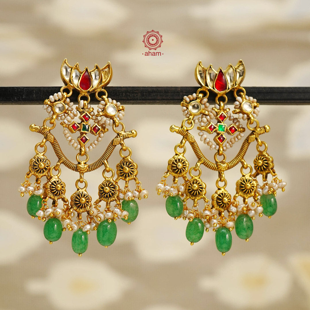 Expertly crafted in silver with a lustrous gold polish, these Kundan Lotus Earrings are an exquisite addition to any outfit. Featuring stunning kundan stones, delicate pearls, and vibrant green drops, these earrings embody elegance and grace. Elevate your style with these beautiful and free-flowing earrings.