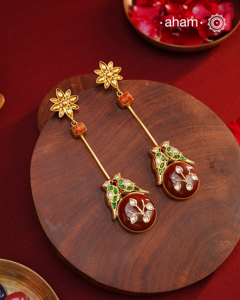 These Double Parrot Gold Polish Silver Earrings feature a unique combo of semi precious stone inlay work, two kundan parrots, raw coral highlights, and a beautiful flower top. Crafted in 92.5 silver with a stunning gold polish, these long shoulderduster earrings will add elegance to any outfit.