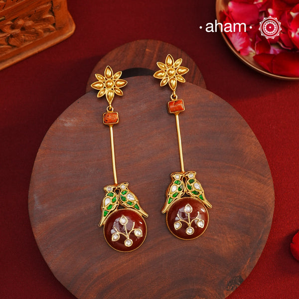 These Double Parrot Gold Polish Silver Earrings feature a unique combo of semi precious stone inlay work, two kundan parrots, raw coral highlights, and a beautiful flower top. Crafted in 92.5 silver with a stunning gold polish, these long shoulderduster earrings will add elegance to any outfit.