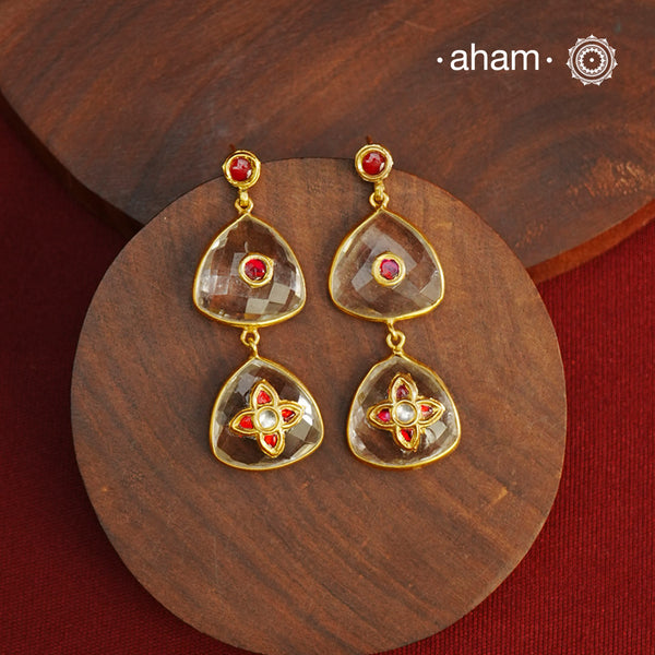 These Clear Quartz Gold Polish Silver Earrings are set in silver and feature exquisite kundan inlay work, blending traditional craftsmanship with contemporary style. Perfectly suited for Indo-Western ensembles, they add a touch of elegance and sophistication to your look. Crafted with attention to detail, these earrings enhance your outfit with their red stone contrast and subtle gold polish, making them a versatile accessory for special occasions.