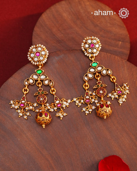 These Festive Gold Polish Silver Earrings feature traditional craftsmanship from South India in a modern design. Made with 92.5 silver, these earrings are adorned with kemp work and pearls, giving them a touch of elegance. Dipped in gold polish for added luster.