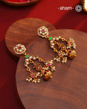 These Festive Gold Polish Silver Earrings feature traditional craftsmanship from South India in a modern design. Made with 92.5 silver, these earrings are adorned with kemp work and pearls, giving them a touch of elegance. Dipped in gold polish for added luster.