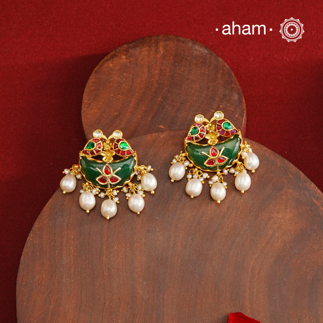 Statement gold polish earring from our heritage collection with a beautiful green stone center and pearl drops. Handcrafted using traditional methods in 92.5 sterling silver with gold polish. Pair these with your ethnic outfits this festive season to ace your look.