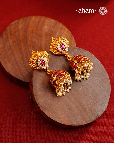 Traditional jhumkies showcasing exquisite Kemp work, meticulously crafted in 92.5% silver with a fine gold polish finish. Adorned with delicate pearls, they blend classic elegance with expert craftsmanship, making them a timeless addition to any jewelry collection.
