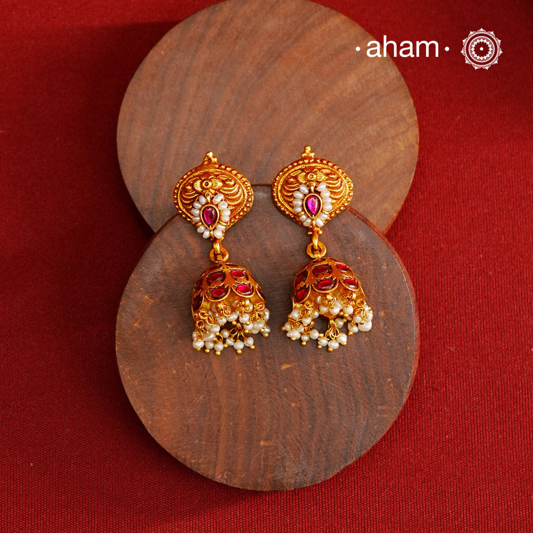 Traditional jhumkies showcasing exquisite Kemp work, meticulously crafted in 92.5% silver with a fine gold polish finish. Adorned with delicate pearls, they blend classic elegance with expert craftsmanship, making them a timeless addition to any jewelry collection.