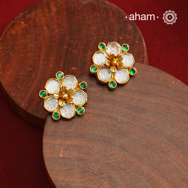 Crafted in 92.5% sterling silver with a refined gold polish, these petite flower studs feature intricate kundan detailing accented by vibrant green stones. Their elegant design blends traditional artistry with modern sophistication, making them an ideal accessory for both everyday wear and special occasions.
