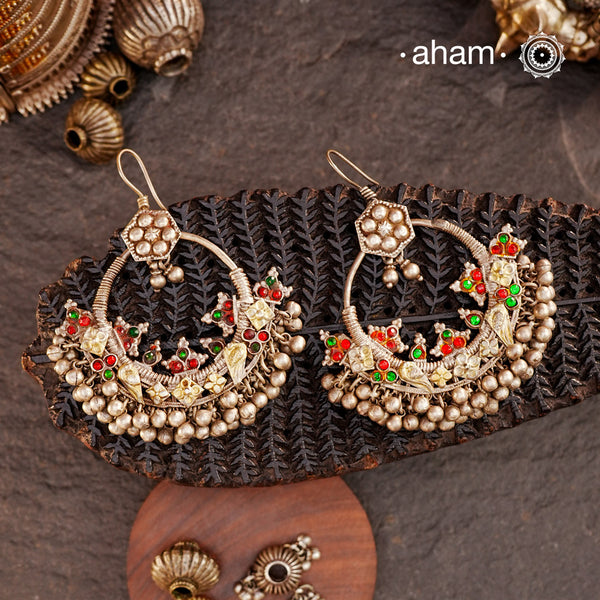 A classic design from Rajasthan's tribal heritage, these Tribal Silver Bali Earrings feature a delicate curve adorned with red and green stones and a cluster of ghungroos at the bottom, adding rhythm and movement. We have added a hook on the top for ease of wear. Handcrafted in silver, these balis perfectly capture the essence of traditional tribal jewellery. Please note the earrings are sightly heavy.