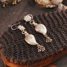 Celebrate timeless tradition with our Tribal Ambi Silver Earrings, featuring a striking Ambi (Mango) bead adorned with delicate ghungroos at the bottom. The top showcases stamp work flower, a hallmark of tribal craftsmanship from India. Handcrafted in&nbsp;silver, these earrings embody the beauty of vintage tribal jewellery — perfect for those seeking a blend of heritage and charm.