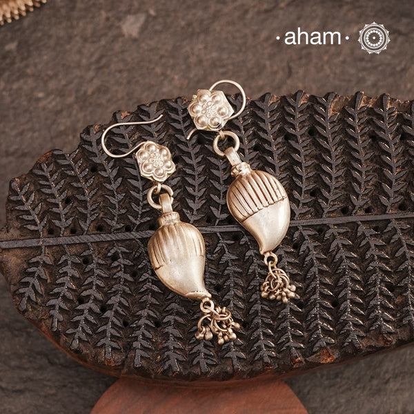 Celebrate timeless tradition with our Tribal Ambi Silver Earrings, featuring a striking Ambi (Mango) bead adorned with delicate ghungroos at the bottom. The top showcases stamp work flower, a hallmark of tribal craftsmanship from India. Handcrafted in&nbsp;silver, these earrings embody the beauty of vintage tribal jewellery — perfect for those seeking a blend of heritage and charm.