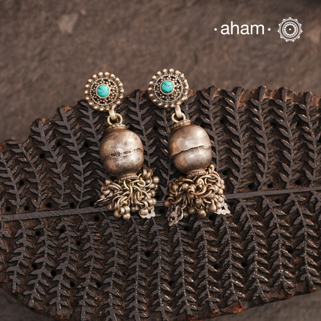 These Tribal Silver Earrings feature a vintage tribal bead adorned with mini ghungroos for added detail. The craftsmanship and blue stud add a touch of tradition and uniqueness to these earrings. Perfect for those who appreciate a distinct and traditional design.