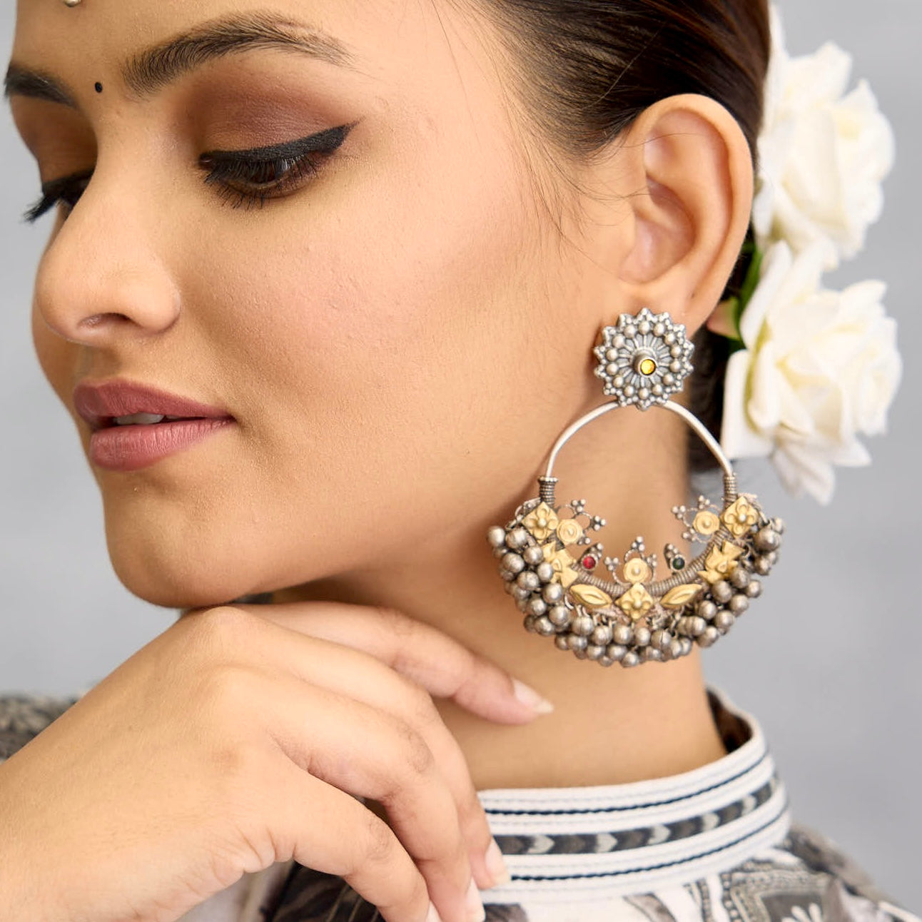 A classic design from Rajasthan's tribal heritage, these Tribal Silver Bali Earrings feature a delicate curve adorned with red and green stones and a cluster of ghungroos at the bottom, adding rhythm and movement. We have added a stud on the top for ease of wear. Handcrafted in silver, these balis perfectly capture the essence of traditional tribal jewellery. Please note the earrings are slightly heavy.