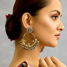 A classic design from Rajasthan's tribal heritage, these Tribal Silver Bali Earrings feature a delicate curve adorned with red and green stones and a cluster of ghungroos at the bottom, adding rhythm and movement. We have added a stud on the top for ease of wear. Handcrafted in silver, these balis perfectly capture the essence of traditional tribal jewellery. Please note the earrings are slightly heavy.