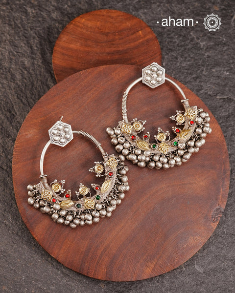 A classic design from Rajasthan's tribal heritage, these Tribal Silver Bali Earrings feature a delicate curve adorned with red and green stones and a cluster of ghungroos at the bottom, adding rhythm and movement. We have added a hook on the top for ease of wear. Handcrafted in silver, these balis perfectly capture the essence of traditional tribal jewellery. Please note the earrings are sightly heavy.