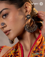 A classic design from Rajasthan's tribal heritage, these Tribal Silver ChandBali Earrings feature a delicate curve adorned with a cluster of ghungroos at the bottom, adding rhythm and movement. To enhance comfort and style, we’ve attached a flower stud at the top for easy wear. Handcrafted in silver, these balis perfectly capture the essence of traditional tribal jewellery.
