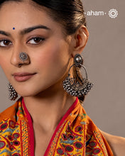A classic design from Rajasthan's tribal heritage, these Tribal Silver ChandBali Earrings feature a delicate curve adorned with a cluster of ghungroos at the bottom, adding rhythm and movement. To enhance comfort and style, we’ve attached a flower stud at the top for easy wear. Handcrafted in silver, these balis perfectly capture the essence of traditional tribal jewellery.