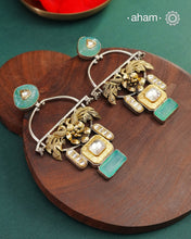 Statement Noori two tone earrings with green semi precious stone setting. Handcrafted in 92.5 sterling silver with elegant peacock motif.&nbsp;Style this up with your favourite ethnic or fusion outfits to complete the look.