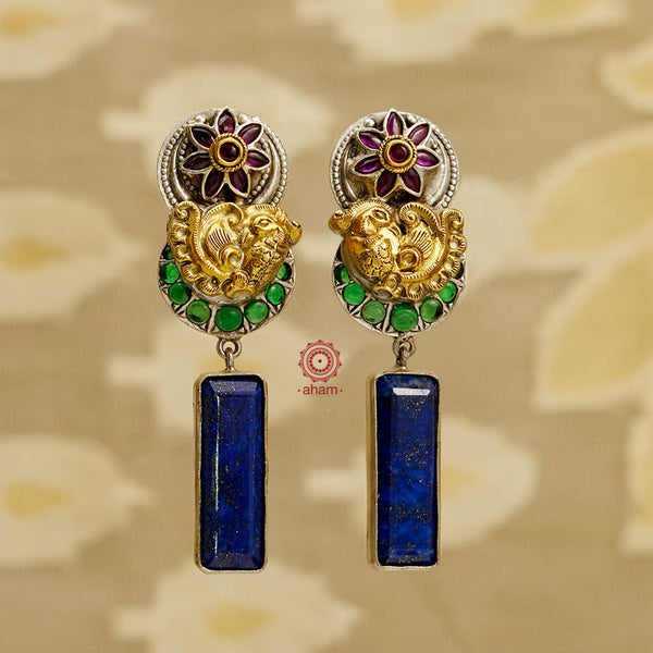Elevate your style with our Noori Peacock Two Tone Silver Earrings. Crafted with intricate nakshi peacock and kemp flower designs, these elegant earrings feature a stunning lapiz drop. Handcrafted in 92.5 silver, each pair is one of a kind. Stand out with these unique and exquisite earrings.
