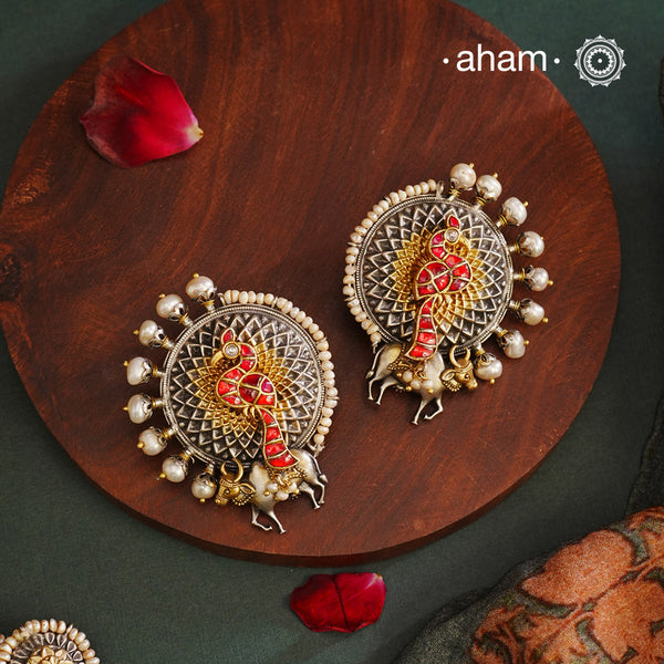 Noori peacock two tone statement studs in 92.5 sterling silver. Handcrafted earrings with beautiful kundan peacock and a detailed cow motifs. Style this up with your favourite ethnic or fusion outfit.