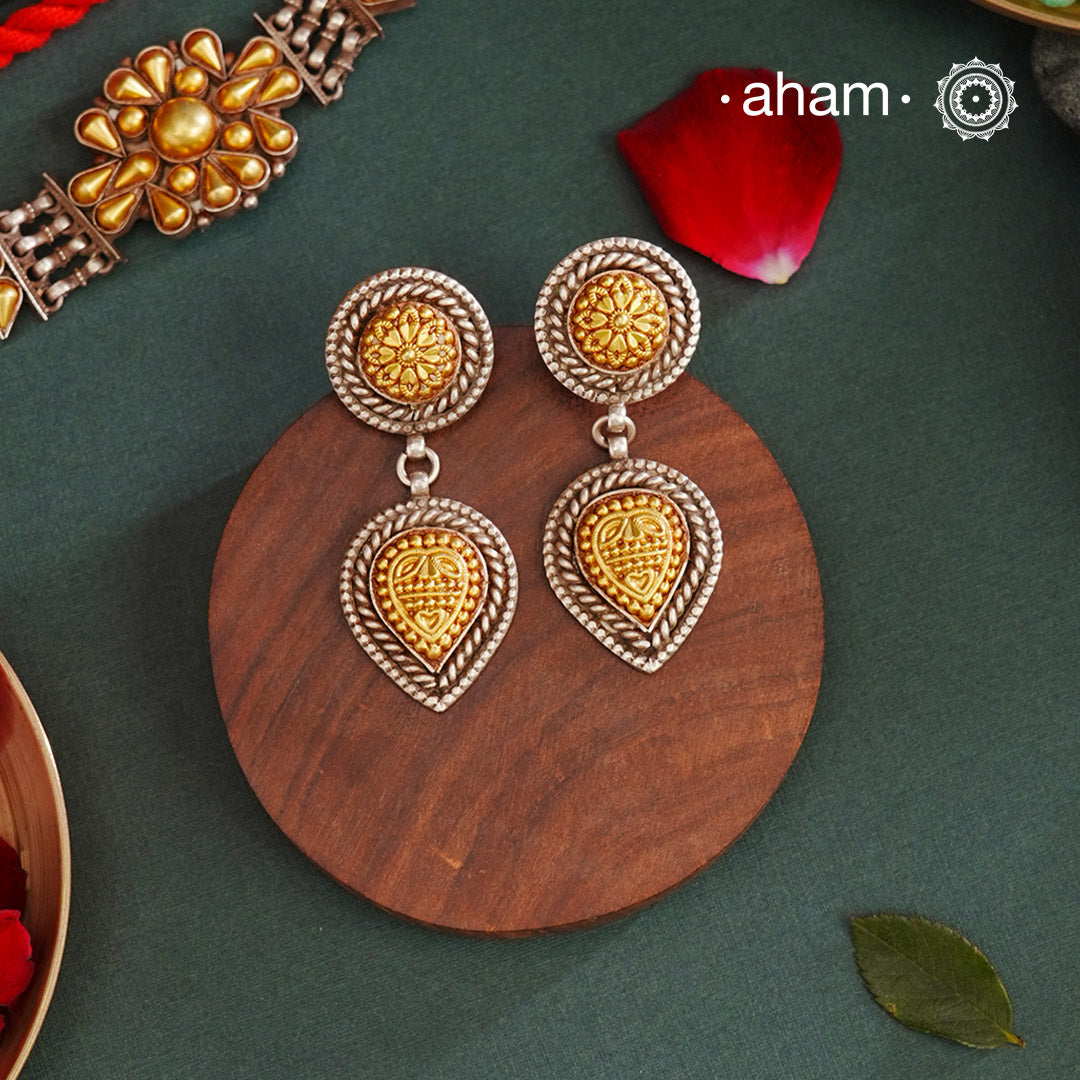 Enhance your style with the timeless elegance of the Dual Tone Silver Earrings. Handcrafted by skilled karigars in Barmer, Rajasthan, this earring features traditional Bandhel work, where a thin sheet of hand beaten 22 carat gold is set on 92.5 silver using a unique wax filling technique. A classic representation of Indian craftsmanship.