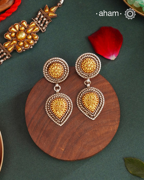 Enhance your style with the timeless elegance of the Dual Tone Silver Earrings. Handcrafted by skilled karigars in Barmer, Rajasthan, this earring features traditional Bandhel work, where a thin sheet of hand beaten 22 carat gold is set on 92.5 silver using a unique wax filling technique. A classic representation of Indian craftsmanship.