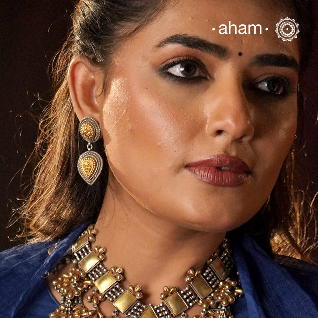 Enhance your style with the timeless elegance of the Dual Tone Silver Earrings. Handcrafted by skilled karigars in Barmer, Rajasthan, this earring features traditional Bandhel work, where a thin sheet of hand beaten 22 carat gold is set on 92.5 silver using a unique wax filling technique. A classic representation of Indian craftsmanship.