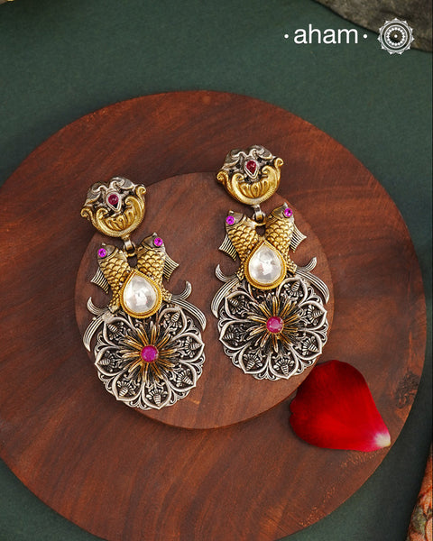 Introducing Noori Two Tone Fish Silver Earrings - a unique and exquisite pair perfect for any occasion. These dual tone earrings feature intricate fishes on both sides, adding a touch of whimsy to its elegant design. Crafted with 92.5 silver and adorned with a stunning quartz polki highlight, these earrings will make a statement and elevate any look with its touch of gold.