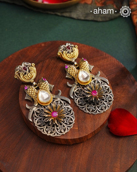 Introducing Noori Two Tone Fish Silver Earrings - a unique and exquisite pair perfect for any occasion. These dual tone earrings feature intricate fishes on both sides, adding a touch of whimsy to its elegant design. Crafted with 92.5 silver and adorned with a stunning quartz polki highlight, these earrings will make a statement and elevate any look with its touch of gold.