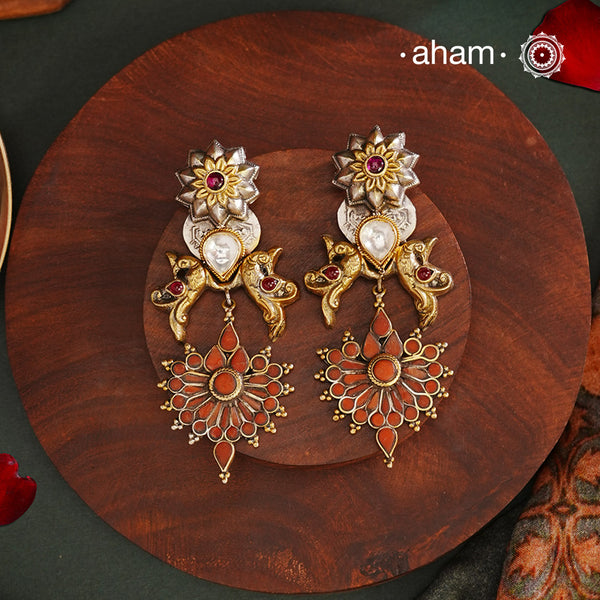 Enhance your look with our Noori Two Tone Silver Earrings! These elegant earrings feature a beautiful coral drop and faux polki in the center, embellished with intricate peacock designs on both sides. The two tone finish adds a touch of sophistication to any outfit. Elevate your style with these stunning earrings.