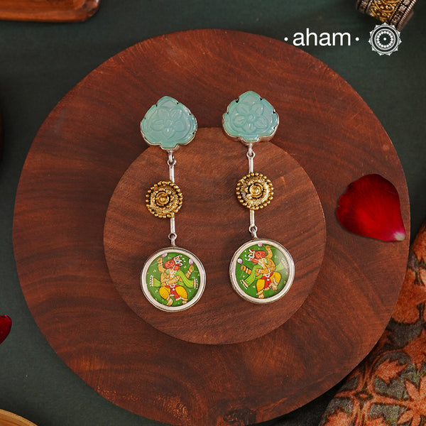 These Noori Two Tone Ganesha Silver Earrings feature a delicate two tone design, adorned with a hand painted miniature ganesha. Made from high quality 92.5 silver, these earrings are both stylish and unique. Elevate your look with the spiritual and cultural significance of these beautifully crafted earrings.