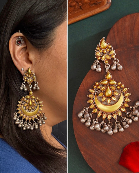 Enhance your style with the timeless elegance of the Dual Tone Silver Earrings. Handcrafted by skilled karigars in Barmer, Rajasthan, this earring features traditional Bandhel work, where a thin sheet of hand beaten 22 carat gold is set on 92.5 silver using a unique wax filling technique. A classic representation of Indian craftsmanship.